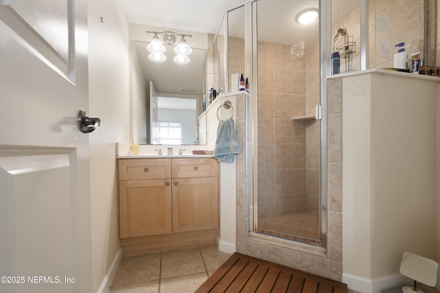 full bathroom featuring tile patterned floors, vanity, baseboards, and a shower stall