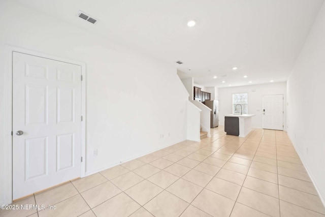unfurnished living room featuring light tile patterned flooring, a sink, recessed lighting, and visible vents