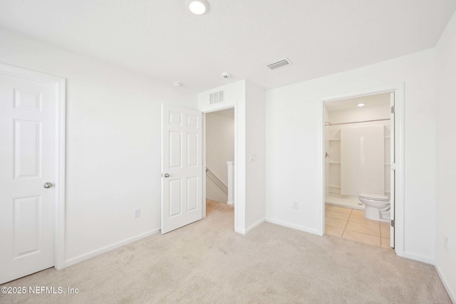unfurnished bedroom featuring baseboards, carpet floors, ensuite bathroom, and visible vents