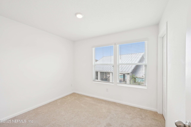 unfurnished room with light carpet and baseboards