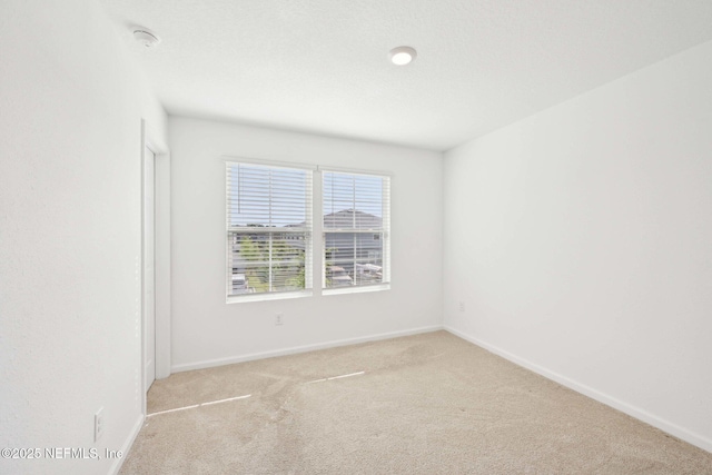 empty room featuring baseboards and light colored carpet