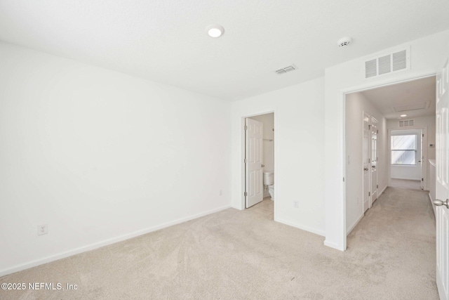 unfurnished room with baseboards, visible vents, and light colored carpet