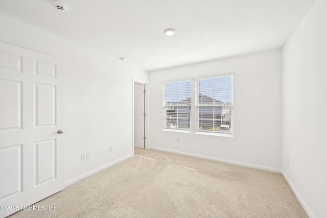 carpeted empty room featuring baseboards