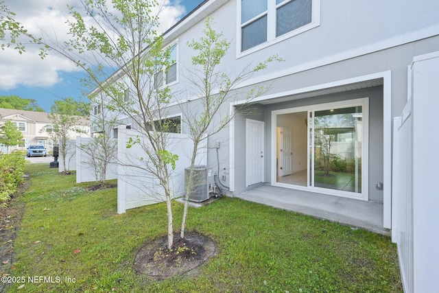 exterior space featuring central AC unit, stucco siding, and a yard
