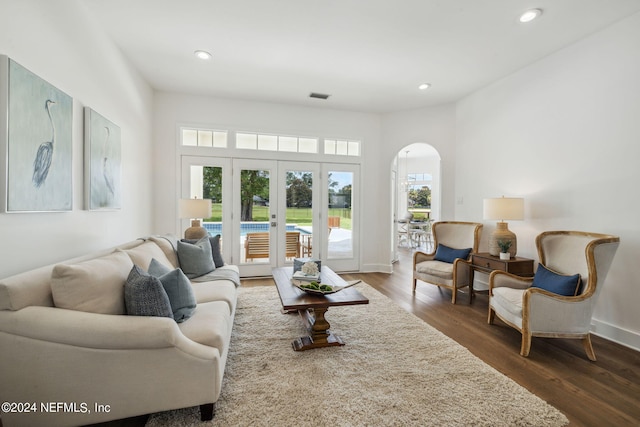 living room featuring arched walkways, french doors, recessed lighting, and wood finished floors