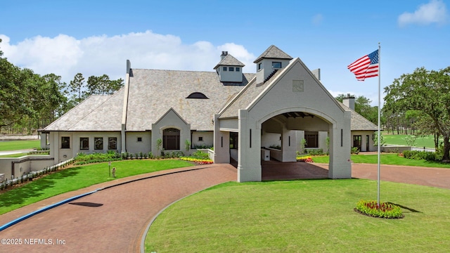 view of front of property with stucco siding, a chimney, and a front lawn