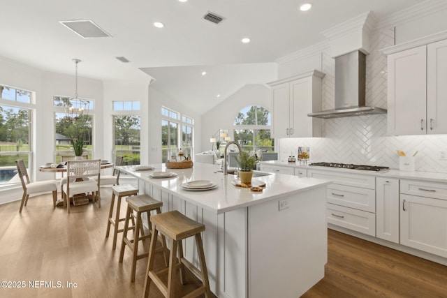 4520 Swilcan Bridge Ln N, Jacksonville, FL 32224 - kitchen featuring a sink, wall chimney range hood, stainless steel gas stovetop, a kitchen island with sink, and light countertops