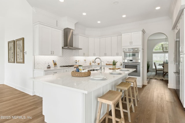 4520 Swilcan Bridge Ln N, Jacksonville, FL 32224 - kitchen featuring stainless steel double oven, wall chimney exhaust hood, arched walkways, a kitchen bar, and a sink