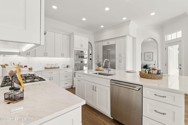 4520 Swilcan Bridge Ln N, Jacksonville, FL 32224 - kitchen with stainless steel appliances, a sink, arched walkways, light stone counters, and decorative backsplash