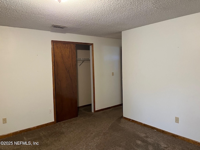unfurnished bedroom with visible vents, a closet, baseboards, a textured ceiling, and carpet
