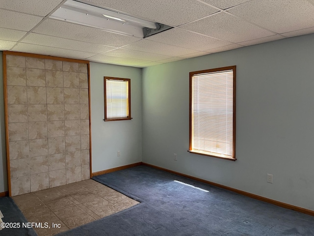 unfurnished room with baseboards, carpet, and a drop ceiling