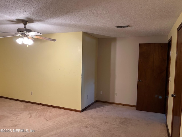 spare room featuring a ceiling fan, a textured ceiling, visible vents, and light carpet