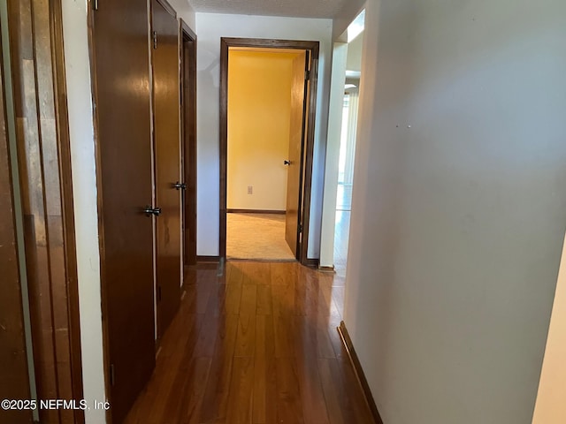 hall featuring dark wood-type flooring and baseboards