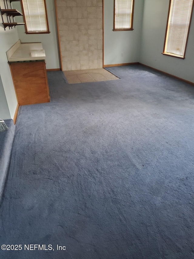 unfurnished living room featuring baseboards and carpet