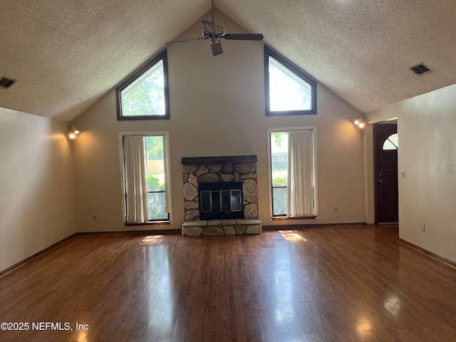 1933 Timucua Trl, Middleburg, FL 32068 - unfurnished living room featuring a textured ceiling, high vaulted ceiling, a ceiling fan, wood finished floors, and a stone fireplace