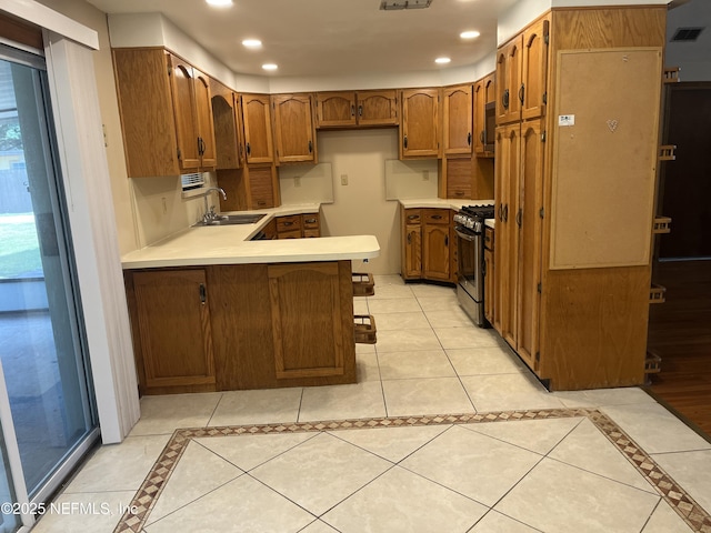 1933 Timucua Trl, Middleburg, FL 32068 - kitchen featuring stainless steel gas range oven, a peninsula, brown cabinetry, inlaid floor details, and recessed lighting
