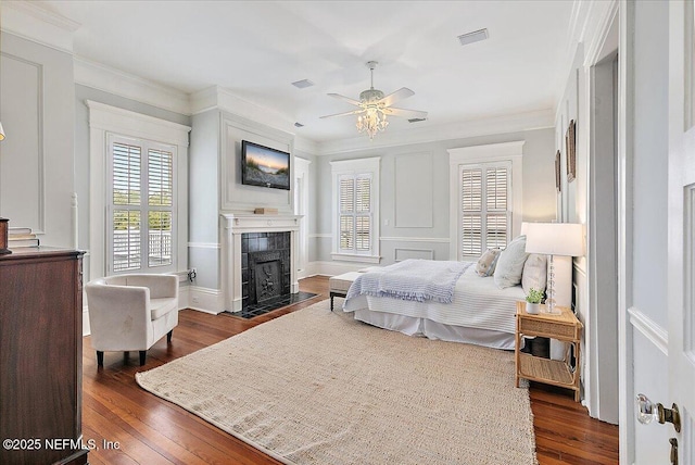 bedroom featuring crown molding, a tile fireplace, and dark wood-style flooring