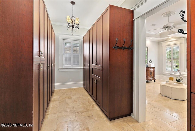 corridor with baseboards, crown molding, stone tile flooring, and a chandelier