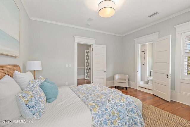 bedroom with visible vents, crown molding, baseboards, wood finished floors, and ensuite bath