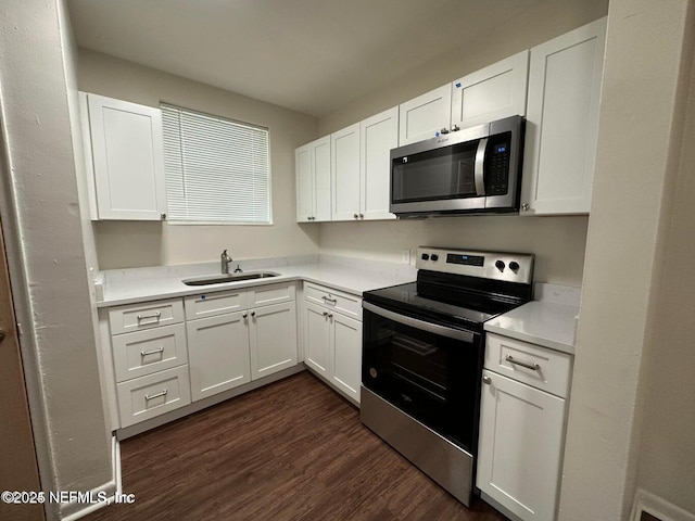 3047 Post St, Jacksonville, FL 32205 - kitchen featuring dark wood-style flooring, white cabinets, light countertops, appliances with stainless steel finishes, and a sink