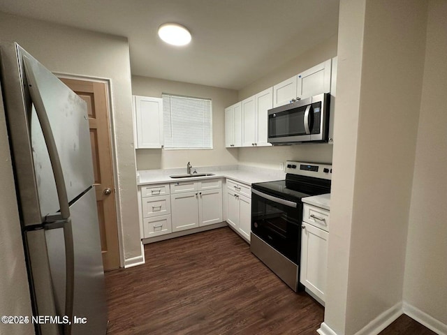3047 Post St, Jacksonville, FL 32205 - kitchen featuring light countertops, dark wood-type flooring, a sink, white cabinets, and appliances with stainless steel finishes