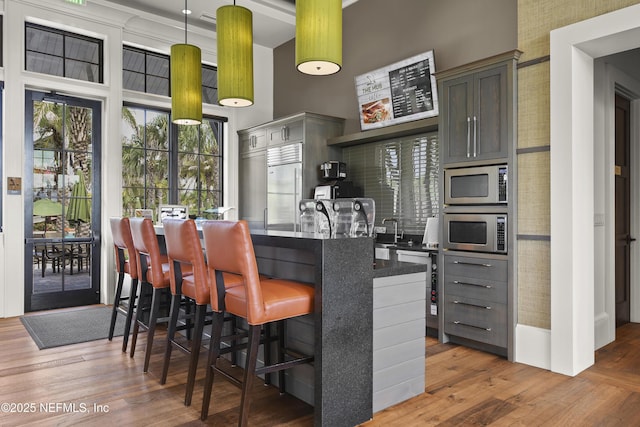 489 Windley Dr, Saint Augustine, FL 32092 - kitchen with decorative light fixtures, built in appliances, a kitchen breakfast bar, hardwood / wood-style flooring, and a towering ceiling