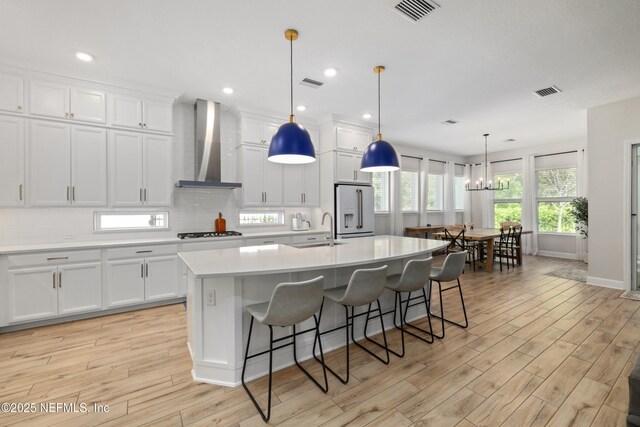 489 Windley Dr, Saint Augustine, FL 32092 - kitchen with high end white refrigerator, wall chimney range hood, an island with sink, gas cooktop, and visible vents