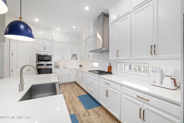 489 Windley Dr, Saint Augustine, FL 32092 - kitchen with wall chimney exhaust hood, a sink, light wood-type flooring, stainless steel appliances, and decorative backsplash