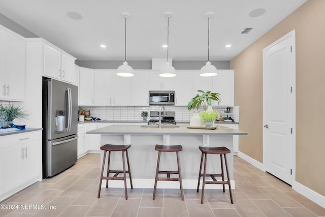 kitchen featuring a sink, tasteful backsplash, visible vents, a kitchen bar, and appliances with stainless steel finishes
