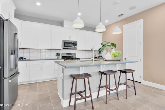 kitchen with stainless steel appliances, a sink, visible vents, backsplash, and a breakfast bar area