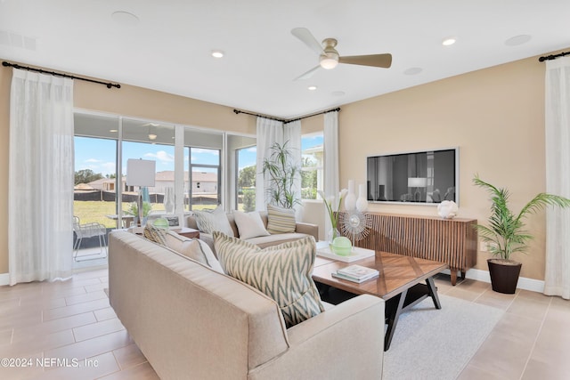 living area with light tile patterned flooring, visible vents, baseboards, and ceiling fan