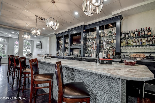 bar with a chandelier, hanging light fixtures, visible vents, and a community bar
