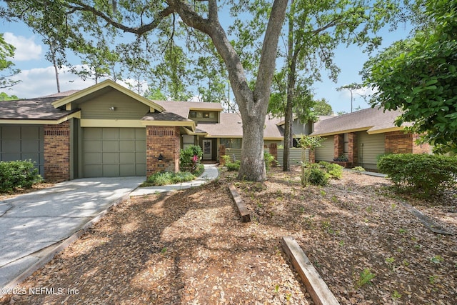 view of front of home with brick siding, driveway, a shingled roof, and a garage