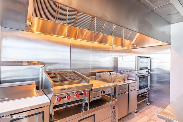 29 Stargaze Ln, Saint Augustine, FL 32095 - kitchen with stainless steel countertops, light wood-style flooring, exhaust hood, stainless steel oven, and gray cabinetry