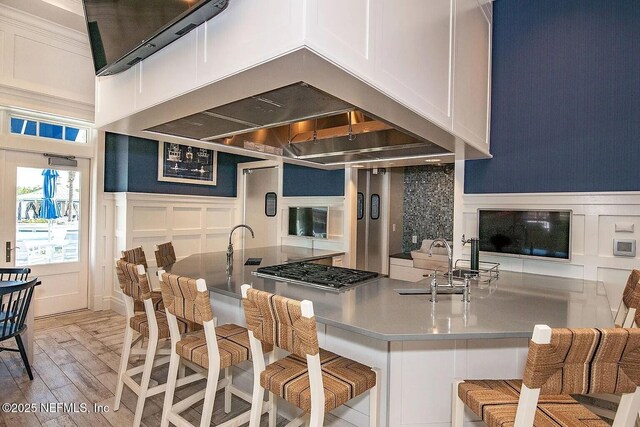 29 Stargaze Ln, Saint Augustine, FL 32095 - kitchen with a decorative wall, stainless steel gas cooktop, a kitchen bar, light wood-type flooring, and white cabinetry