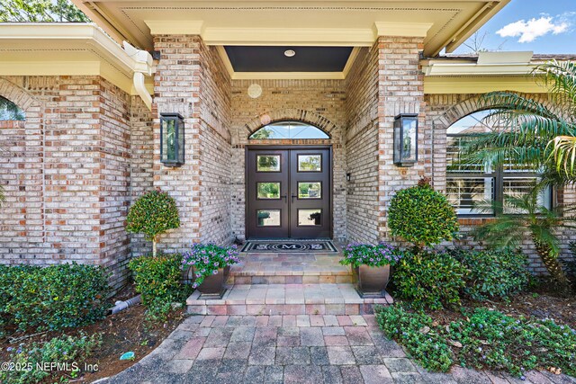 view of exterior entry with brick siding and french doors