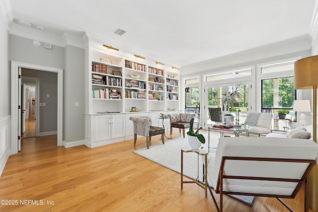 interior space featuring light wood finished floors, baseboards, visible vents, and crown molding