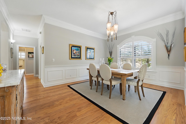 dining area with visible vents, a notable chandelier, light wood-style flooring, and ornamental molding