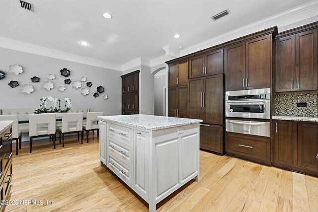 kitchen featuring visible vents, light wood-style flooring, oven, paneled fridge, and a warming drawer