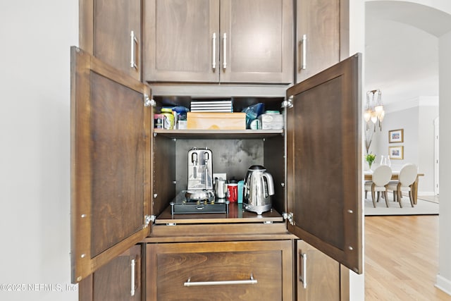 details with crown molding, open shelves, light wood-type flooring, baseboards, and arched walkways