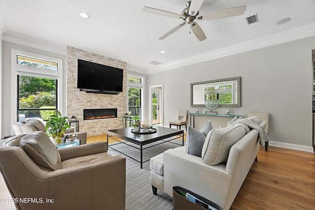 living room featuring visible vents, wood finished floors, ornamental molding, and a fireplace