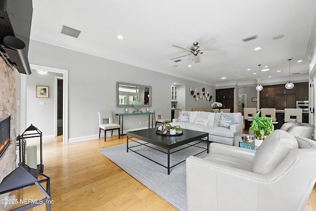 living room featuring visible vents, light wood finished floors, ceiling fan, ornamental molding, and recessed lighting
