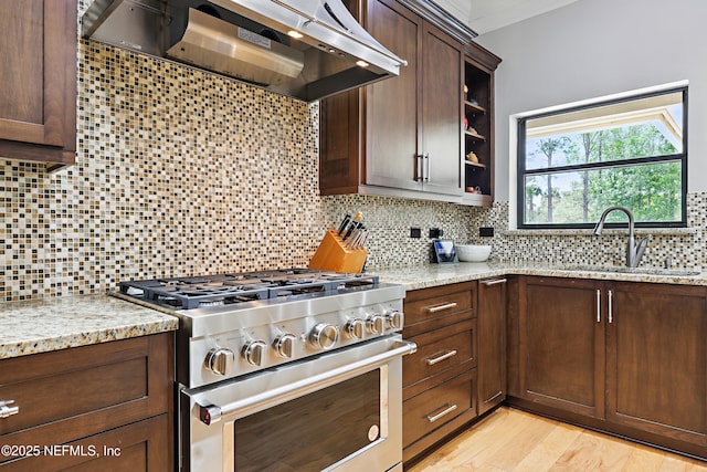 kitchen featuring a sink, backsplash, exhaust hood, and high end stove