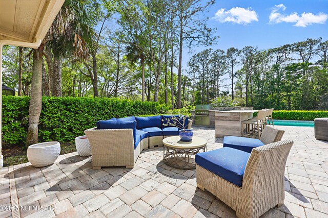 view of patio featuring area for grilling, an outdoor living space, exterior kitchen, and a fenced in pool