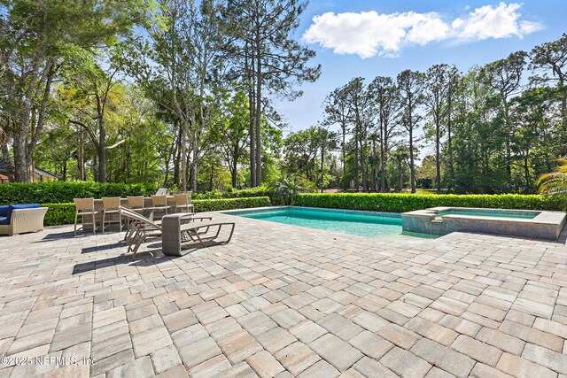 view of pool with a pool with connected hot tub and a patio area