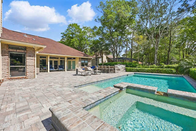 view of swimming pool with a pool with connected hot tub and a patio area