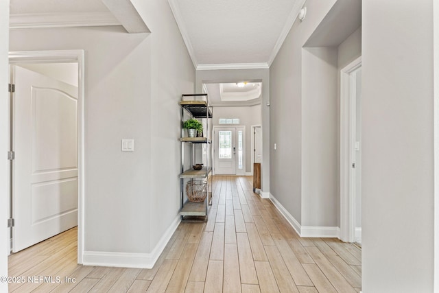 hall featuring light wood-type flooring, crown molding, and baseboards
