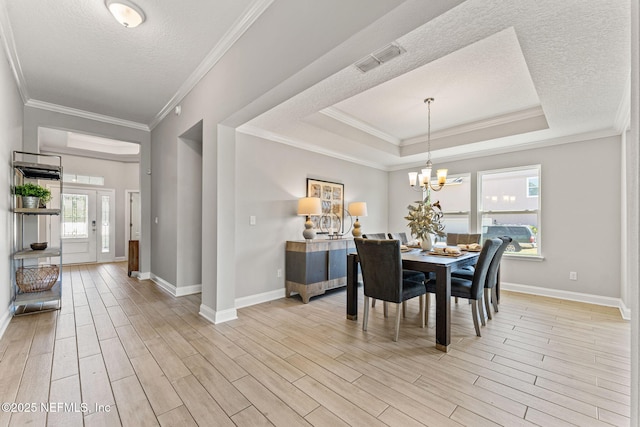 dining room featuring a textured ceiling, light wood-style flooring, visible vents, and baseboards