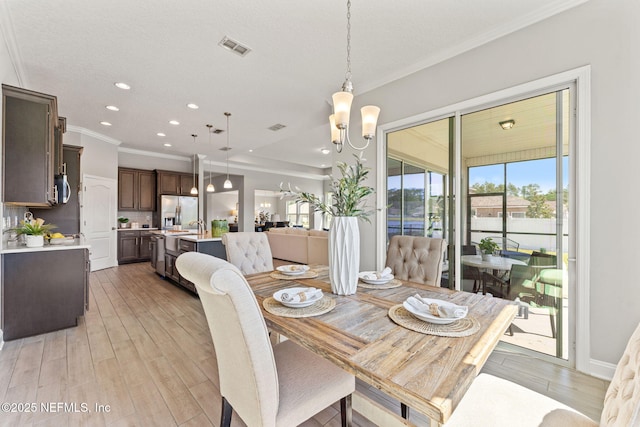 dining space with crown molding, a chandelier, light wood-style floors, visible vents, and recessed lighting