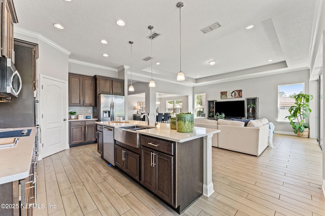 kitchen with light wood finished floors, dark brown cabinets, visible vents, light countertops, and appliances with stainless steel finishes